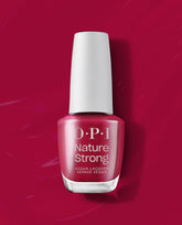 OPI Nature Strong Vegan Nail Lacquer in A Bloom with a View stands upright, showing a rosy berry fall nail color with a white cap against a glossy magenta polish-swatch background.