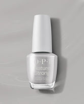OPI Nature Strong Vegan Nail Lacquer in Dawn of a New Gray stands upright, showing a soft light gray shade in a clear bottle with a white cap on a gray background, a trending neutral nail color.
