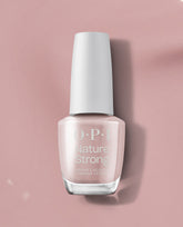 OPI Nature Strong Vegan Nail Lacquer in Kind of a Twig Deal stands upright, showing a soft pale pink shade with a white cap on a dusty pink background, ideal for subtle fall nail colors.