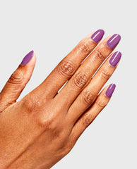 A hand displays glossy almond-shaped purple nails painted with OPI RapiDry Bright Back at It, a vibrant choice among fall nail colors, against a light gray studio background.