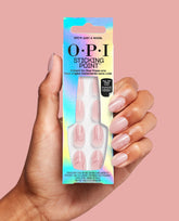 Hand holding OPI’m Just a Whirl Sticking Point instant no-glue press-on nails, showing trending pale pink almond nails with subtle swirl lines against a soft pink background.