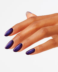Hand with almond-shaped nails painted in Abstract After Dark, a deep shimmery midnight purple OPI nail polish nail lacquer, angled against a clean white background to showcase the bold, glossy manicure color for evening looks.