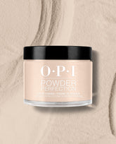 OPI Powder Perfection Berlin There, Doin’ That dipping powder jar sits on a textured beige powder surface, showing a soft taupe shade for fall nail colors.
