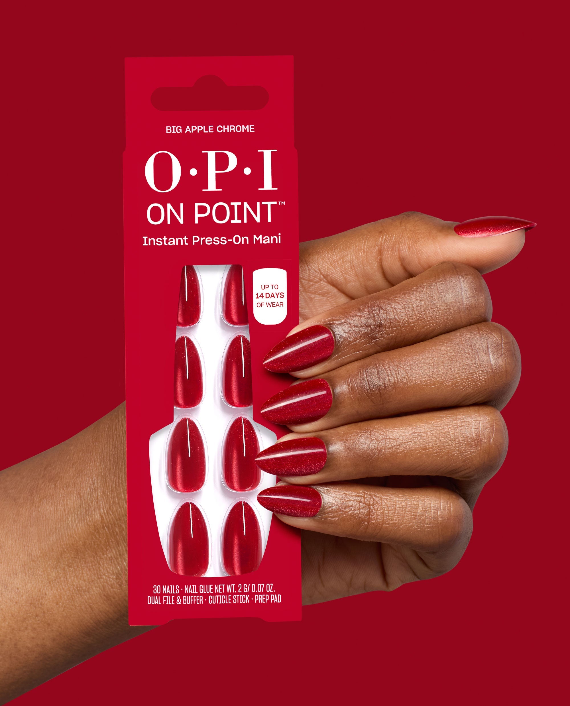 OPI On Point Big Apple Chrome press-on nails are held beside a hand wearing glossy red chrome almond tips, with 30 nails and manicure tools shown on red packaging, ideal for fall nail colors.