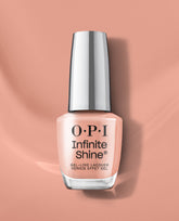 OPI Infinite Shine Boots in Barcelona gel-like lacquer bottle in a soft peach nude shade, standing against a matching peach background for polished fall nail colors.