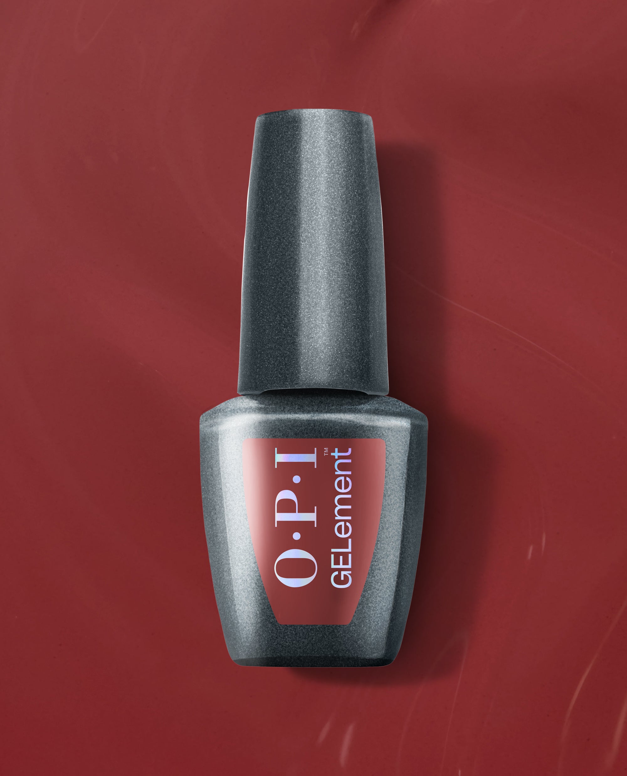 OPI GelColor Como Se Dice Gel-ous? at-home gel nail polish bottle with smoky charcoal shimmer and red label on a deep red background, a bold pick for fall nail colors.