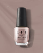 OPI nail polish bottle of Crimp and Proper nail lacquer standing upright, showcasing a soft nude-beige shade with black textured cap, centered on a matching taupe background for a clean, modern product display.