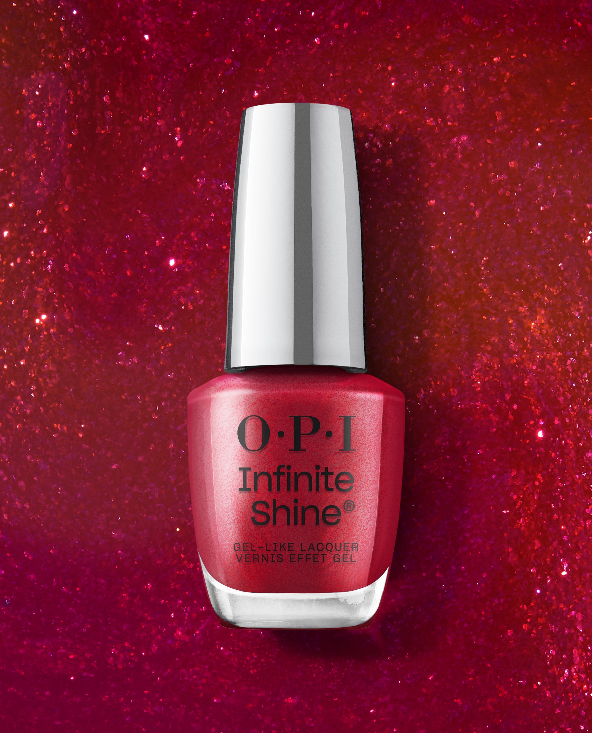 OPI Infinite Shine Deer Valley Spice red shimmer gel-like lacquer bottle stands centered on a sparkling red glitter background, showcasing bold fall nail colors.
