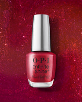 OPI Infinite Shine Deer Valley Spice red shimmer gel-like lacquer bottle stands centered on a sparkling red glitter background, showcasing bold fall nail colors.