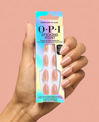Hand holding OPI Sticking Point Double Shot of Glaze press-on nails in glossy nude peach, with matching almond manicure against a peach background, a chic pick for fall nail colors.