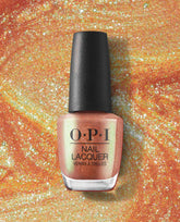 OPI nail polish bottle of #Virgoals nail lacquer standing upright, showcasing a shimmery peach-gold metallic shade against a swirling glittery orange backdrop, highlighting the sparkly, high-shine manicure color.