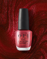 OPI nail polish bottle of CD Rom-antic nail lacquer standing upright, showcasing its shimmery metallic red shade against a swirling, glittery deep red background for a bold, glamorous manicure look.