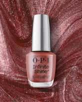 Stellar Tips OPI nail polish Infinite Shine bottle stands upright, showcasing its shimmery rose-gold gel-like lacquer against a swirling metallic red glitter background for a glamorous long-lasting manicure look.