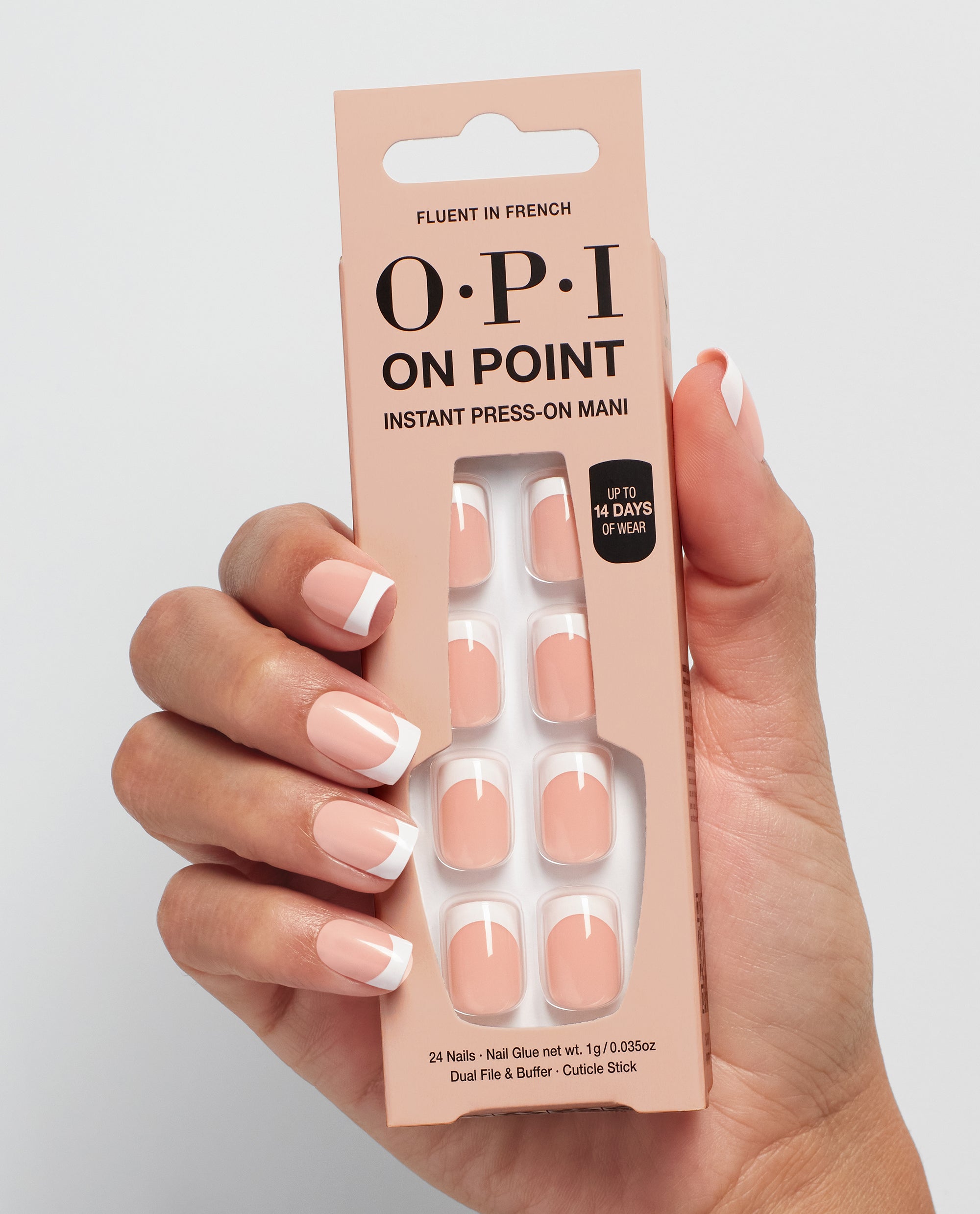 Hand with glossy French manicure holds OPI Fluent in French On Point instant press-on nails in nude and white tips packaging, showcasing a chic nail polish gift set against a clean light gray background.
