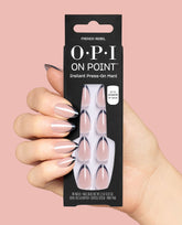 Hand holding OPI On Point French Rebel instant press-on mani packaging, featuring blush nude nails with black French tips, a sleek choice for fall nail colors on a soft pink background.