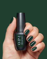 Hand holding OPI GELElement Garden My French At-Home Gel Nail Polish bottle, nails painted glossy deep forest green nail polish, showcasing one of the spring nail colors by OPI against a matching dark green background.