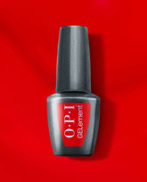 OPI Glossy Goddess at-home gel nail polish bottle in shimmering gunmetal gray stands upright on a vivid red background, a bold metallic shade for fall nail colors.