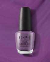 OPI nail polish bottle, shade Grandma Kissed a Gaucho, stands upright showing creamy medium purple nail lacquer against a matching rich violet background, highlighting the salon-quality OPI Nail Lacquer product for manicures and pedicures.