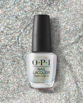 OPI nail polish bottle of I Cancer-tainly Shine nail lacquer standing upright on a sparkling silver glitter background, showcasing its iridescent white shimmer finish for manicures and pedicures.