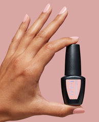 Hand with glossy pale pink nails holds an OPI GELement bottle of I’m the Gloss!, a trending at-home gel nail polish, against a soft pink background.