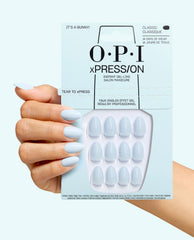 OPI xPRESS/ON It's a Bunny! pale blue oval press-on nails shown on a manicured hand holding the retail pack, featuring instant gel-like salon manicure and 14 days of wear on a light blue background.