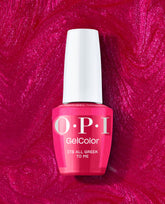 OPI GelColor It’s All Greek to Me gel nail polish bottle in vivid fuchsia pink stands against a shimmering magenta polish swirl, a bold pick for fall nail colors.