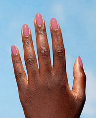 Hand with neatly manicured nails painted in Knowledge is Flower, a dusty rose shade from OPI Nature Strong Vegan Nail Lacquer, held against a soft blue sky background, ideal for showcasing an OPI nail polish gift set color option.
