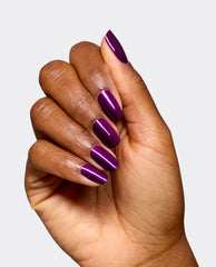 Hand modeling OPI Infinite Shine Louvre Me Lourve Me Not, a glossy deep purple shimmer manicure on long rounded nails against a light gray background, ideal for fall nail colors.