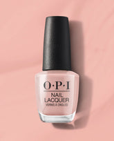 OPI nail polish bottle of Machu Peach-u nail lacquer standing upright, showcasing its soft peachy pink shade against a matching blush background, highlighting the glossy finish and black textured cap for a modern, feminine look.