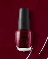 OPI Malaga Wine Nail Lacquer bottle displays a deep burgundy red polish with a black cap, set against a glossy wine-red swatch, ideal for fall nail colors.