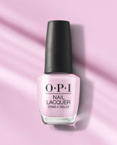 OPI Mod About Me nail lacquer bottle in soft pastel pink with a black textured cap, standing on a pink background with gentle shadows.