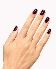 Hand showing glossy deep burgundy manicure with OPI Infinite Shine Mrs. O'Leary's BBQ, a rich wine-red shade for fall nail colors, on a clean white background.