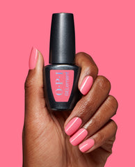 Hand with glossy pink MVPink at-home gel manicure holding an OPI GELElement bottle against a matching pink background, showcasing the OPI nail polish gift set color and shine.