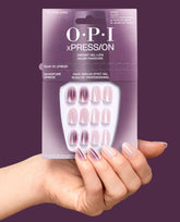 Hand holding OPI xPRESS/ON My Pink Aura short press-on nails in mauve and soft pink shimmer aura designs, shown in packaging as chic fall nail colors.