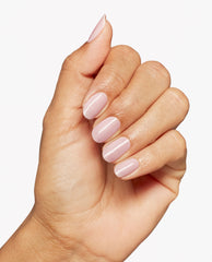 Hand displaying glossy pale pink almond-shaped nails painted with OPI OPI’m a Bubble Bunny nail lacquer against a clean white background.