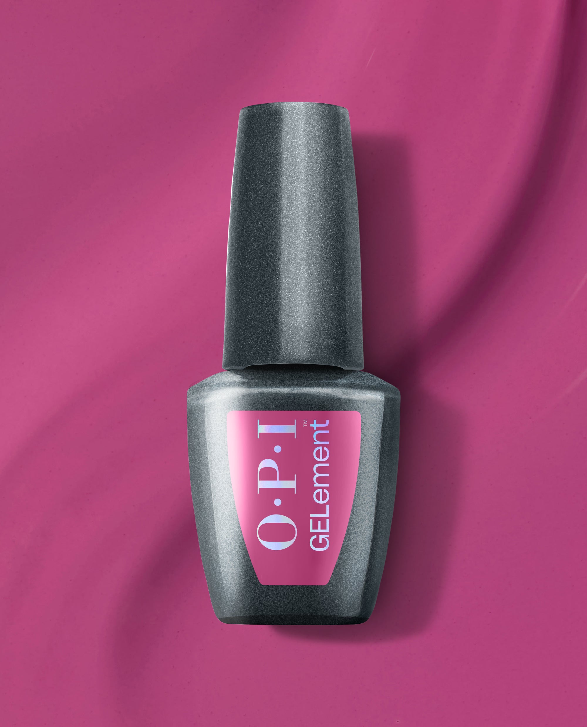 OPI Pompeii Me in Nails at-home gel nail polish bottle with a metallic charcoal finish and pink label, displayed on a vibrant magenta background for bold fall nail colors.