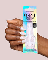 A hand with glossy white rhinestone press-on nails holds the iridescent OPI Sticking Point Princess Treatment box, showing no-glue peel-and-press nails as a chic option for fall nail colors.