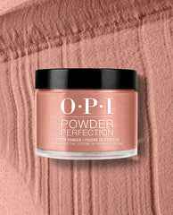 OPI Powder Perfection Route Beer Float dipping powder jar sits on a textured rosy bronze powder swatch, showcasing a shimmering fall nail color with black cap and clear base.