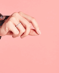 Hand with neatly manicured nails painted in OPI nail polish shade Somewhere Over the Rainbow Mountains softly posed against a solid pink background, showcasing the glossy neutral nail lacquer on short, rounded nails.