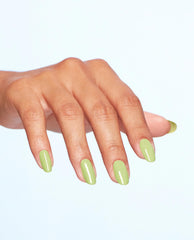 Manicured hand showcases OPI Clear Your Cash dipping powder, a glossy pastel green nail polish, with almond-shaped nails spread against a clean light background, highlighting fresh spring nail colors.