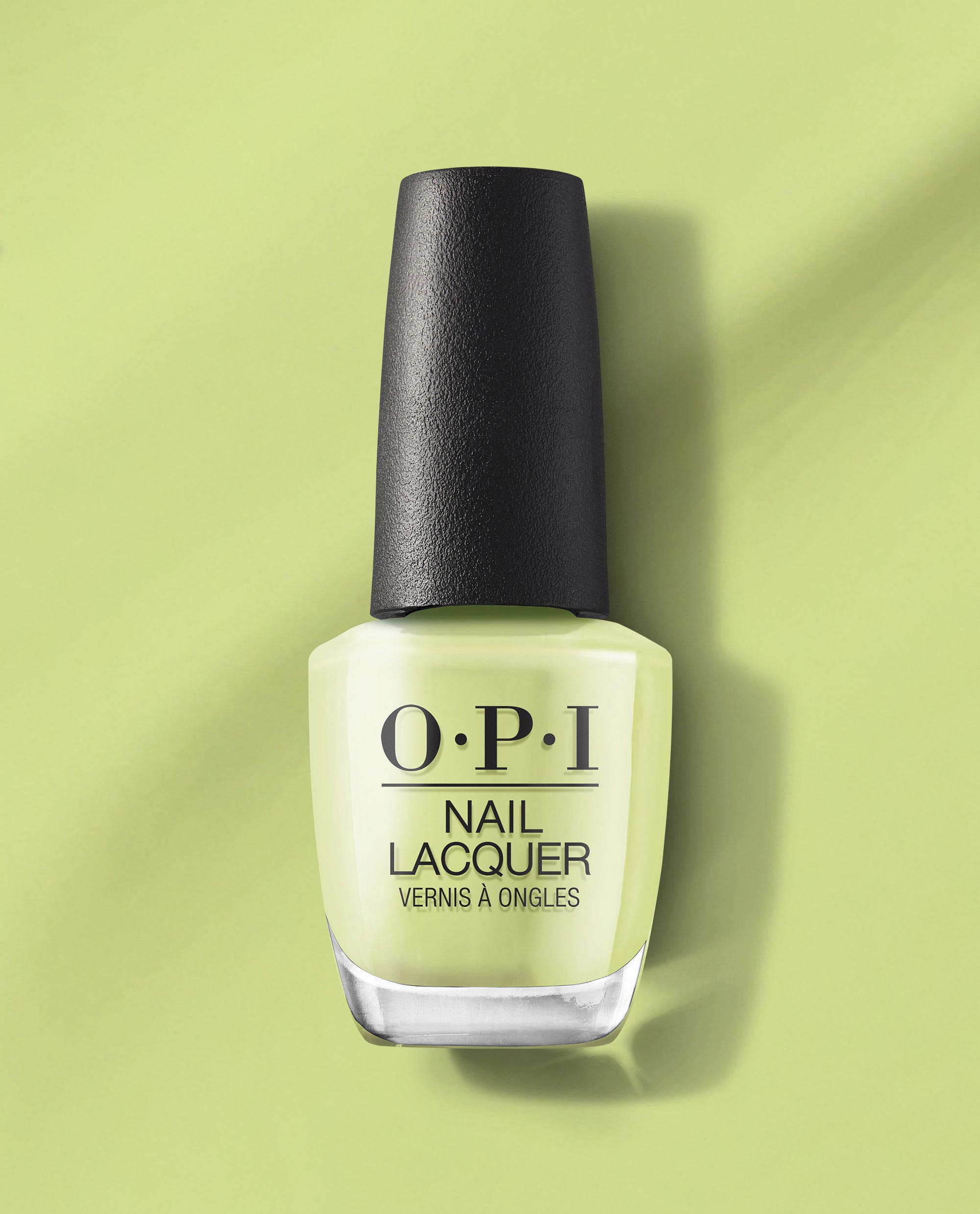 OPI Clear Your Cash nail lacquer stands upright, revealing a creamy pastel green nail polish shade on a matching light-green background, a fresh pick for spring nail colors from OPI.