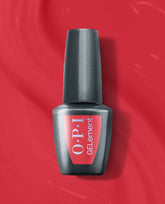 OPI Special O-Cajun at-home gel nail polish bottle stands centered on a glossy red polish background, with a black cap and red OPI GELelement label for a trending red manicure shade.