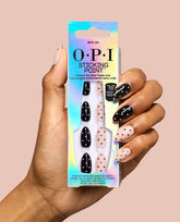 Hand holding OPI Spot On Sticking Point instant no-glue press-on nails in an iridescent box, with black and pale pink polka dot designs for playful fall nail colors.