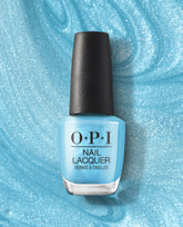 OPI Surf Naked nail lacquer bottle standing upright on shimmering light-blue polish smear background, featuring a sky-blue shade from trending nail colors.