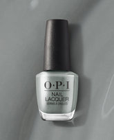 OPI nail polish bottle of Suzi Talks with Her Hands nail lacquer standing upright, showcasing its cool gray shade and black cap against a matching gray background for a modern, minimalist product display.