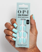 Hand models OPI On Point Suzi Without a Paddle instant press-on nails in glossy pastel aqua, holding the package with matching square nails visible, showcasing OPI trending nail colors on a clean white background.