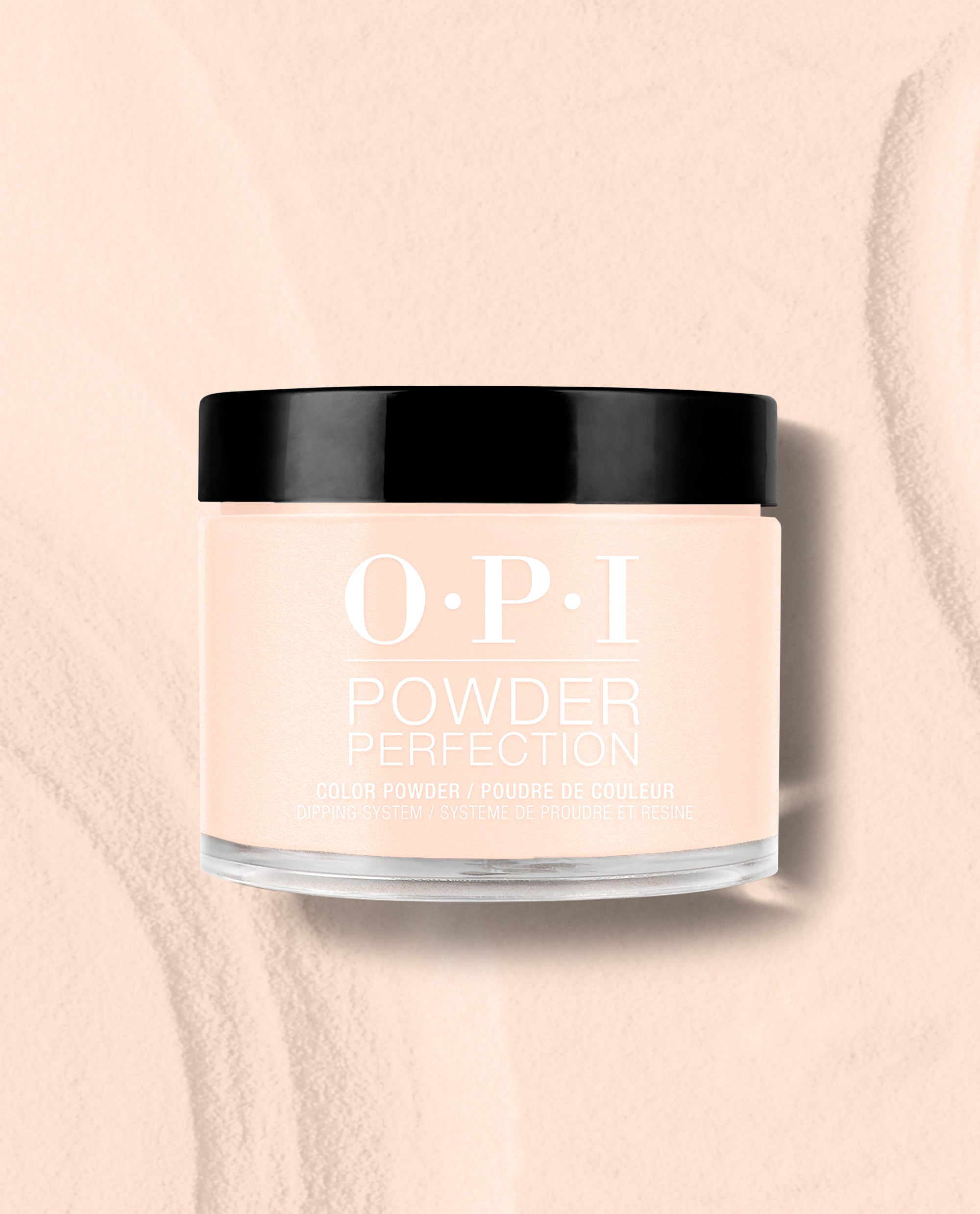 OPI Powder Perfection Throw Me a Wink dipping powder jar in a soft pale peach shade with a black lid, displayed on a matching textured background for fall nail colors.