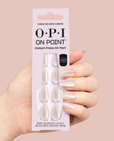Hand holds OPI On Point Throw Me Some Chrome instant press-on mani box, showing pearly chrome almond nails and up to 14 days wear against a soft pink background, ideal for fall nail colors.