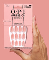 Hand holding OPI Totally Pressed xPRESS/ON Iconic Shades long press-on nails in soft pink, showing the full nail set packaging against a matching blush background, ideal as an OPI nail polish gift set for salon-quality manicures at home.