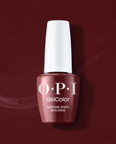 OPI GelColor Vampire State Building gel nail polish bottle in a deep burgundy red shade, standing against a matching glossy red backdrop for rich fall nail colors.